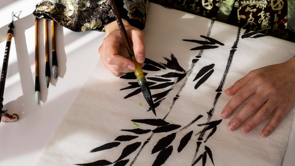 Personne dessinant des bambous à l’encre de Chine avec un pinceau de calligraphie sur du papier hanji