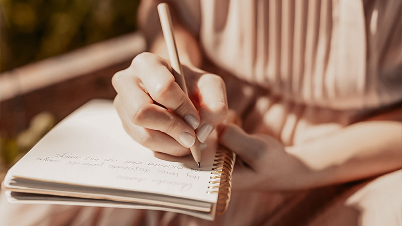 Focus sur la main d'une femme écrivant dans un carnet