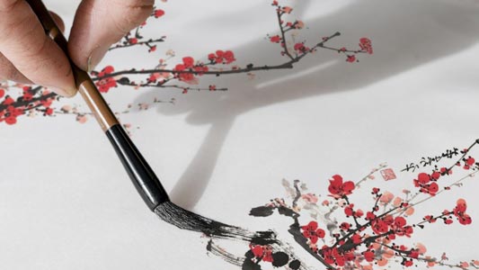 Gros plan sur une main peignant un prunier en fleur dans un style traditionnel coréen